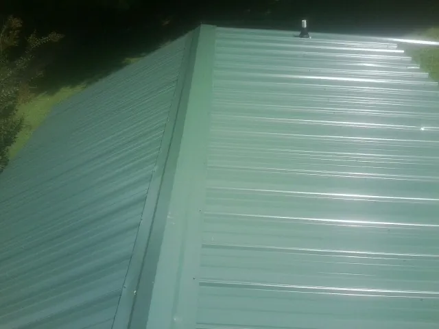 New green metal panels meeting at the ridge of a roof — Flat Roof Repair work by our crew in Elwood