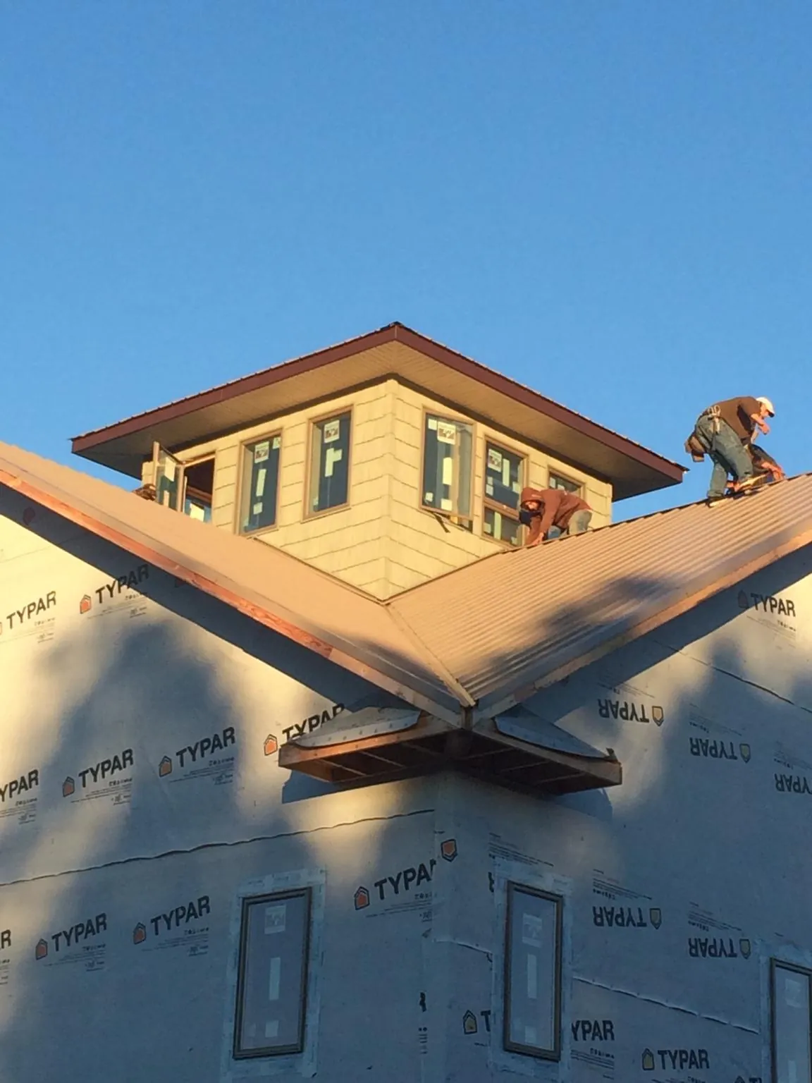 Roofers working around a rooftop cupola on a new metal roof at sunset — Roof Waterproofing in Elwood by Roofing Brothers